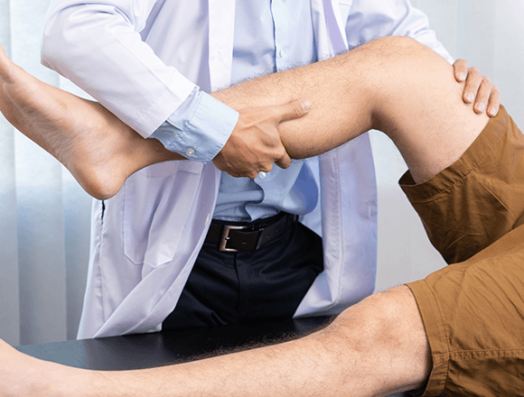 Doctor examining patients knee and performing manual osteopathic therapy